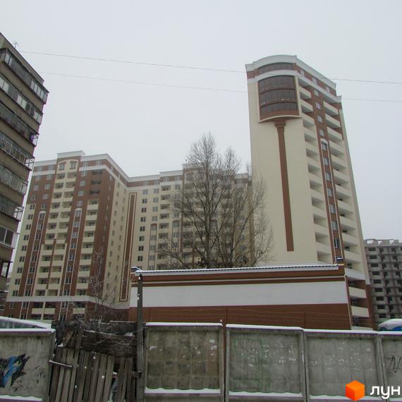 Житловий комплекс Palladium - сучасна новобудова з коричневими та білими фасадами. Навколо будинку розташовані бетонні паркани та дерева.