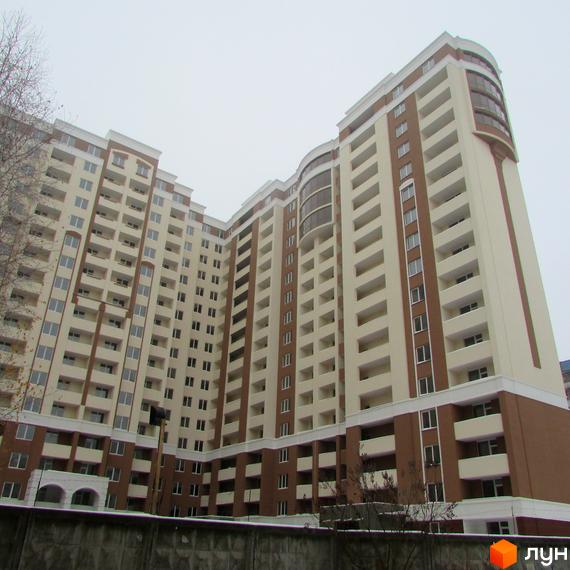 Житловий комплекс Palladium - висотна новобудова з балконами та коричнево-бежевим фасадом. Перед будинком видно бетонний паркан.