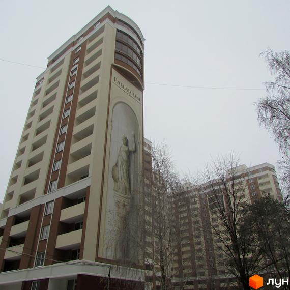 Житловий комплекс Palladium – висотна будівля з колонадою та статуєю на фасаді. Навколо комплексу розташовані дерева.