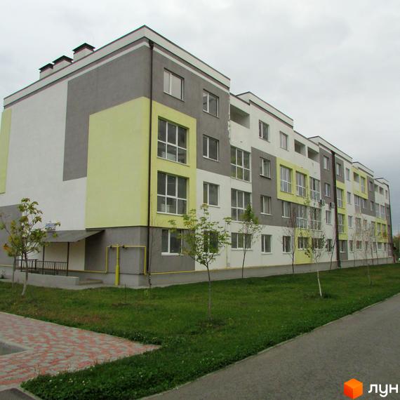 Житловий комплекс Сан Сіті - сучасна новобудова з яскравим фасадом та доглянутою прибудинковою територією. Будинок має багато вікон та балконів, а перед ним розташований зелений газон та доріжка з бруківки.