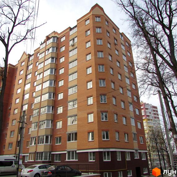 Житловий комплекс Столичний квартал - цегляний будинок з багатьма вікнами та балконами. Навколо будинку дерева та припарковані автомобілі.