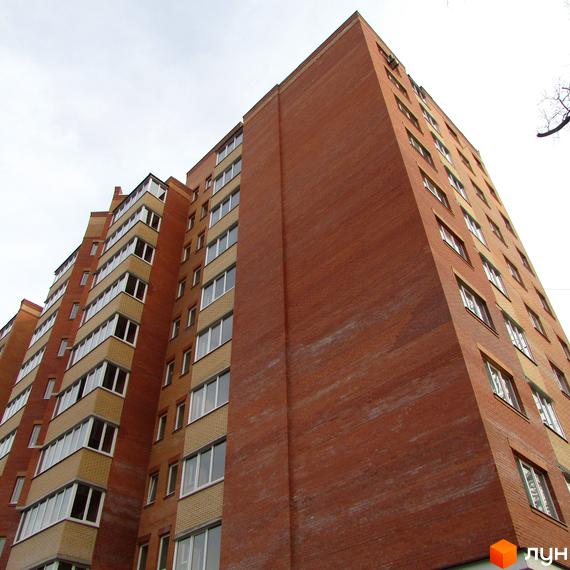 Зовнішній вигляд новобудови ЖК Столичний квартал. Будинок з червоної цегли з численними вікнами та балконами.