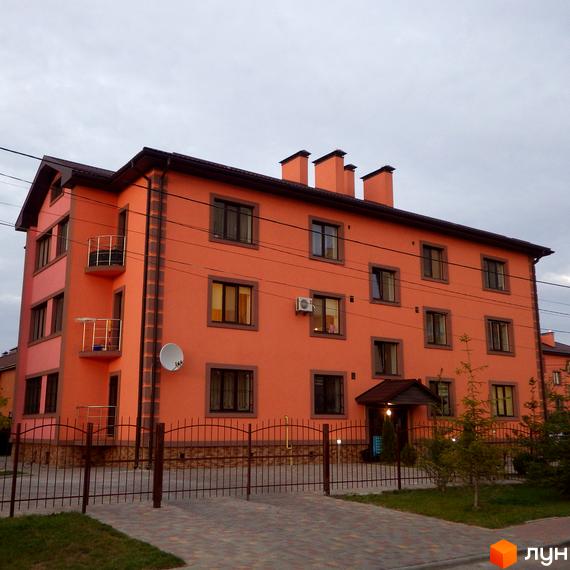 Житловий комплекс Волошковий: фасади будинку в персиковому кольорі з коричневими вікнами та балконами. Огороджена прибудинкова територія з доріжками та зеленими насадженнями.