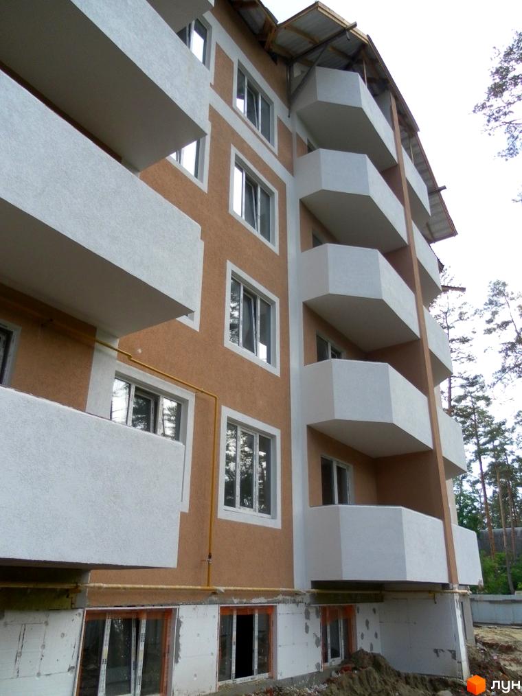 Багатоповерховий будинок з білими балконами та вікнами. Житловий комплекс Родинний пропонує квартири з гарним видом.