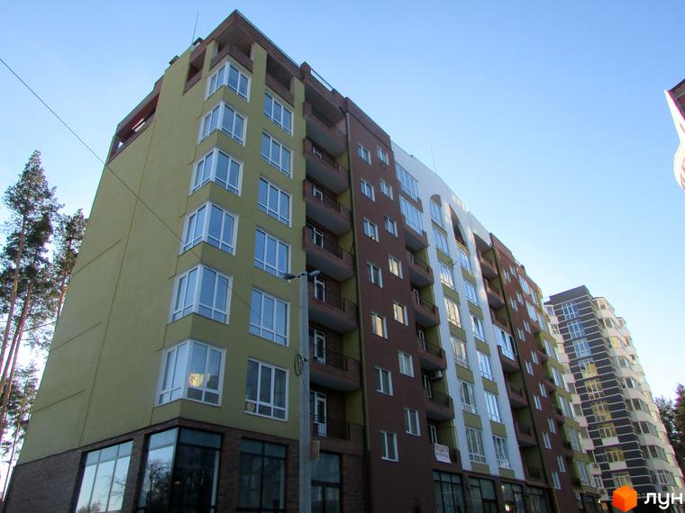 Житловий комплекс Женев'єва - багатоповерховий будинок з коричневою та світло-зеленою обробкою фасаду, великими вікнами та балконами. На передньому плані видно частину прибудинкової території.