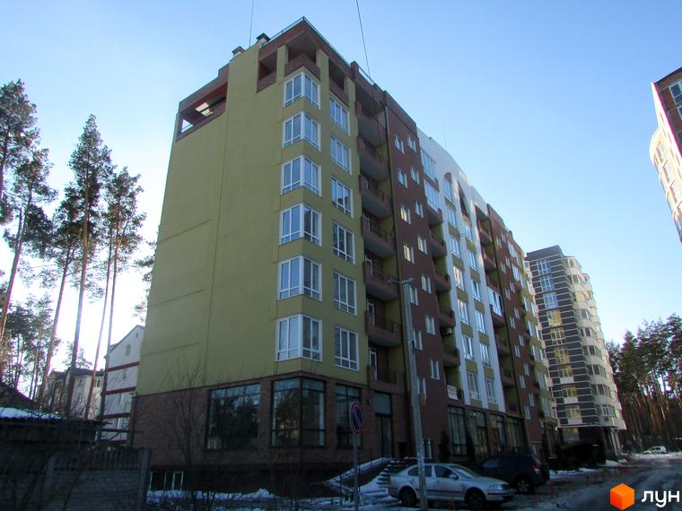 Житловий комплекс Женев'єва - багатоповерхова новобудова з фасадами різних кольорів та великими вікнами. Навколо будівлі дерева та прибудинкова територія.