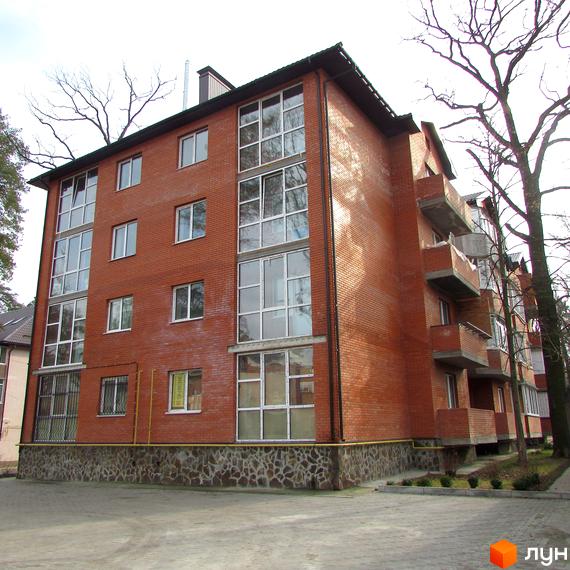 Житловий комплекс Креатив Хаус: цегляний будинок з великими вікнами та балконами. Прибудинкова територія з бруківкою та деревами.