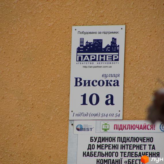 Інформаційна табличка на текстурованій стіні будинку Житлового комплексу Високий за адресою вулиця Висока 10а.