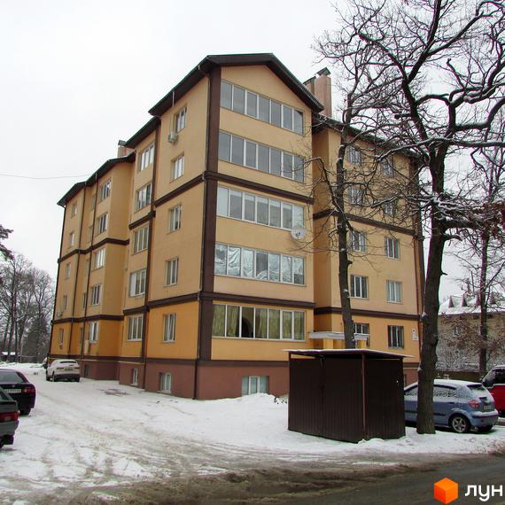 Житловий комплекс Високий: багатоповерховий будинок світло-жовтого кольору з коричневими акцентами взимку. Засніжена прибудинкова територія з деревами та автомобілями.