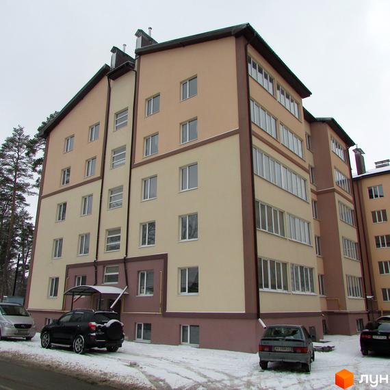 Житловий комплекс Високий: багатоповерховий будинок з бежевим та коричневим фасадом, вікнами та балконами. Прибудинкова територія засніжена, з припаркованими автомобілями.