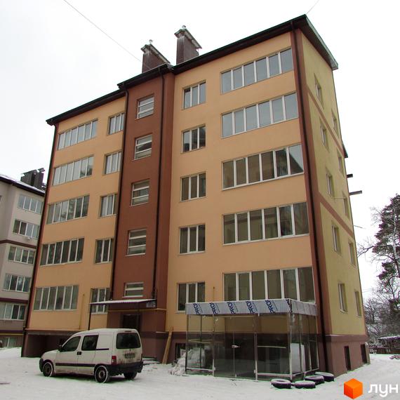 Зовнішній вигляд новобудови ЖК Високий з коричневими та бежевими фасадами, великими вікнами. На прибудинковій території видно білий мінівен та засніжену землю.