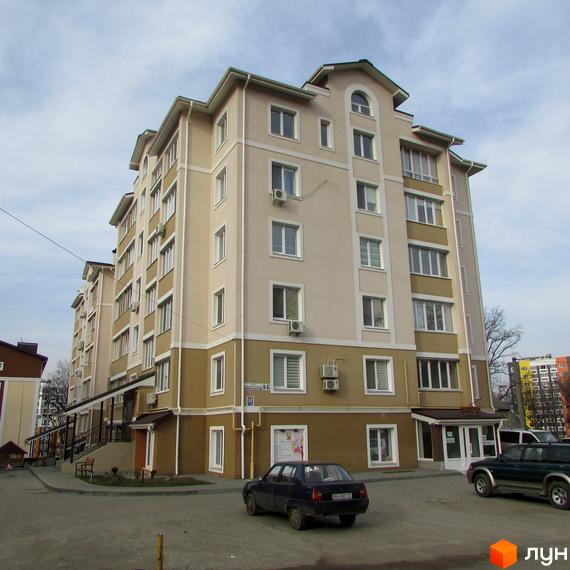 Житловий комплекс на вул. Новооскольська, 8б: багатоповерхова будівля бежевого та коричневого кольорів з комерційними приміщеннями на першому поверсі.