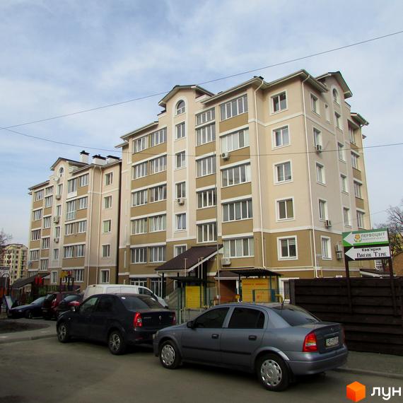Житловий комплекс на вул. Новооскольска, 8б: багатоквартирний будинок з бежевими та коричневими фасадами, прибудинкова територія з припаркованими авто.