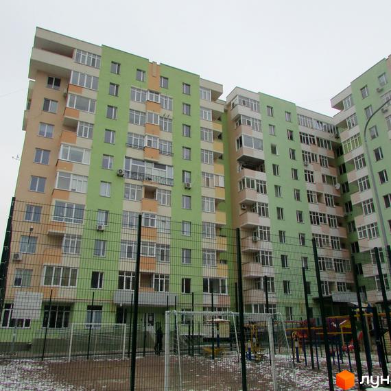 Зовнішній вигляд багатоповерхового будинку в Житловому комплексі Київські Зорі. На фото прибудинкова територія з дитячим майданчиком.