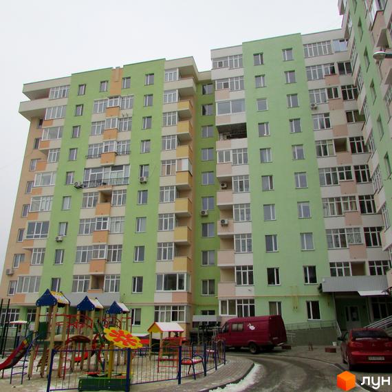 Зовнішній вигляд багатоповерхового будинку в Житловому комплексі Київські Зорі. На передньому плані дитячий майданчик.