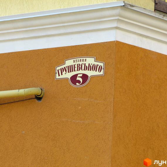 Зовнішній вигляд будинку за адресою вулиця Грушевського, 5. Фасад будинку пофарбований у помаранчевий колір, на стіні висить адресна табличка.