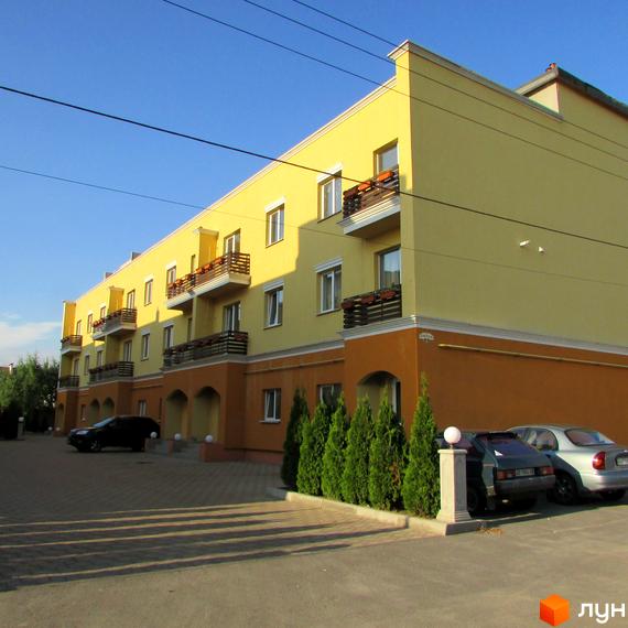 Зображення фасаду Житлового комплексу Петровский дворик. На фото будівля з балконами та автомобілі на прибудинковій території.