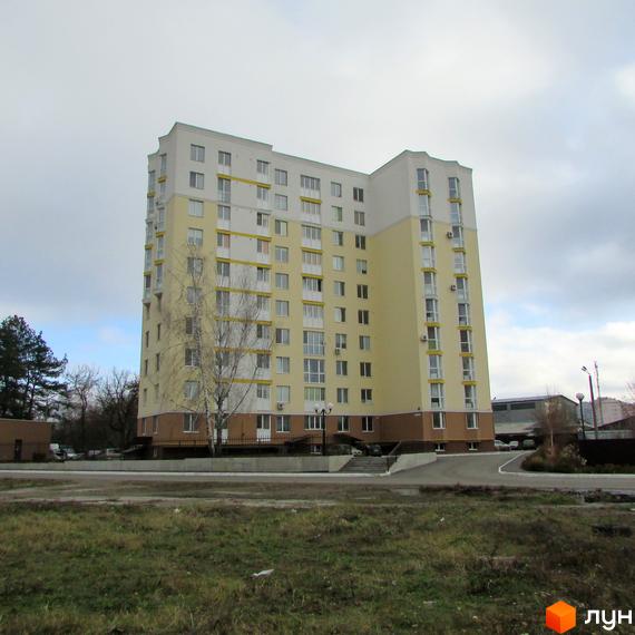 Зовнішній вигляд багатоповерхового будинку на вулиці Тараса Шевченка, 4б. Навколо будинку видно зелену траву та дерева.