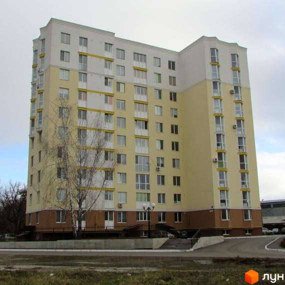 Зовнішній вигляд багатоповерхового будинку по вул. Тараса Шевченка, 4б. Навколо будинку видно прибудинкову територію з деревами та дорогою.