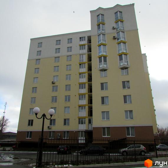 Зображення багатоквартирного будинку по вулиці Тараса Шевченка, 4б. Фасад будівлі жовтого кольору з великими вікнами та балконами.