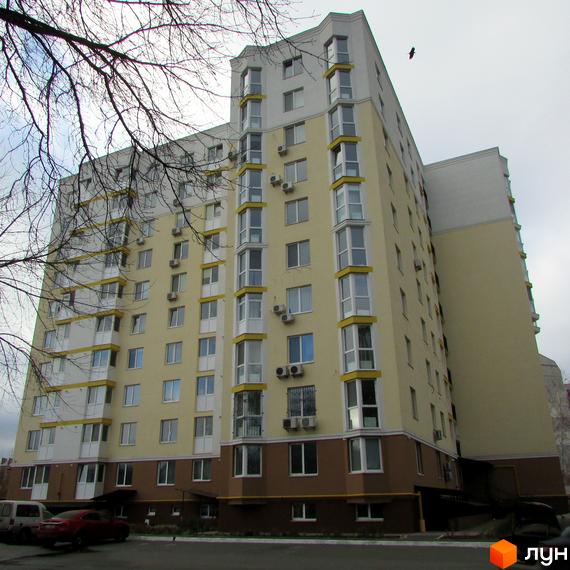 Зображення багатоповерхового будинку на вулиці Тараса Шевченка, 4б. На передньому плані припарковані автомобілі та дерева без листя.