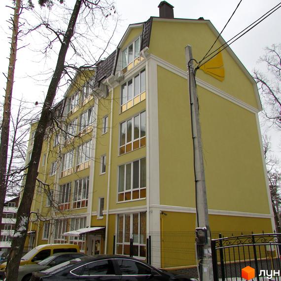 Зображення фасаду Житлового комплексу Пушкінський. Багатоповерховий будинок жовтого кольору з великими вікнами та коричневим дахом.