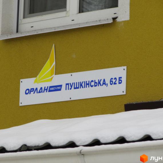 Зовнішній вигляд будинку за адресою Пушкінська, 62Б. Фасад жовтого кольору з білою табличкою та логотипом компанії 