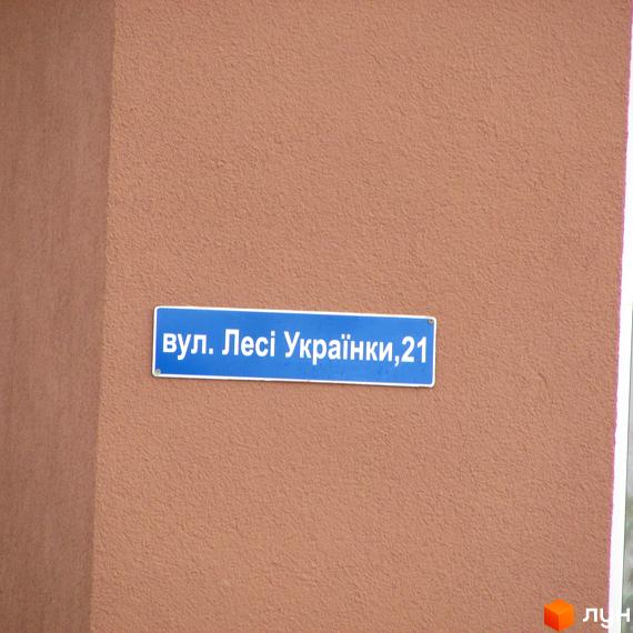 Зображення будинку за адресою вул. Лесі Українки, 21. Фасад будівлі з адресним знаком.