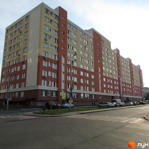 Зображення фасаду багатоповерхового будинку в Житловому комплексі Вишневий затишок. На передньому плані вулиця з пішохідним переходом та припаркованими авто.