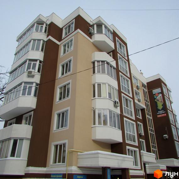 Зовнішній вигляд багатоквартирного будинку в Житловому комплексі Синергія-1. Фасад будинку коричневого та бежевого кольору, великі вікна та балкони.