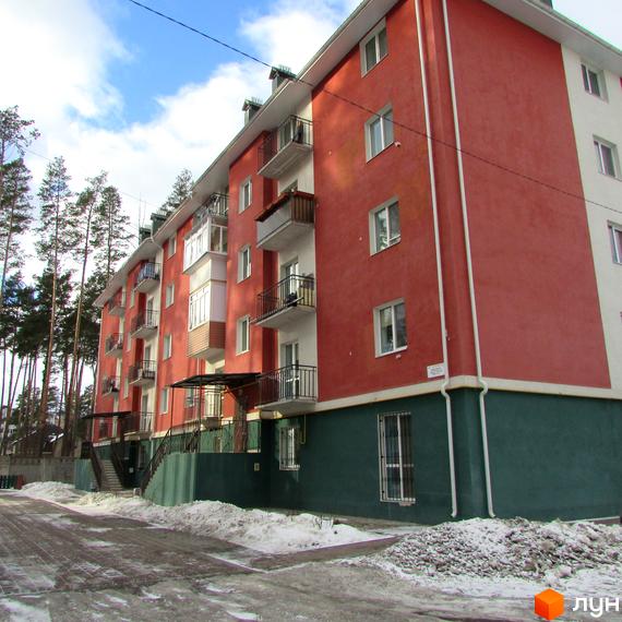 Зображення фасаду та прибудинкової території Житлового комплексу Рильського. Багатоповерховий будинок з балконами та зеленим подвір'ям.