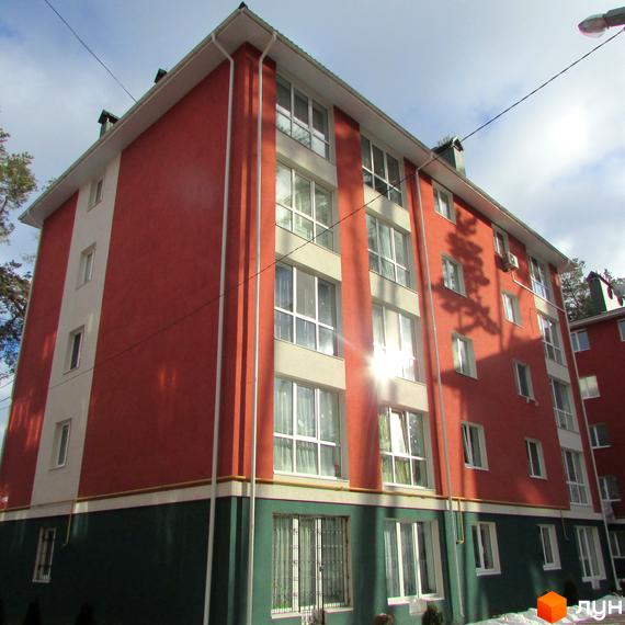 Зображення фасаду та вікон Житлового комплексу Рильського. Багатоповерховий будинок з червоними стінами та великими вікнами.