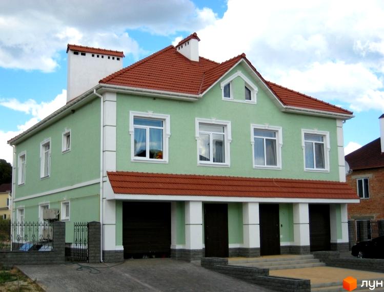 Двоповерховий будинок з теракотовим дахом та світло-зеленими стінами. Перед будинком розташована доглянута прибудинкова територія з воротами та доріжками.