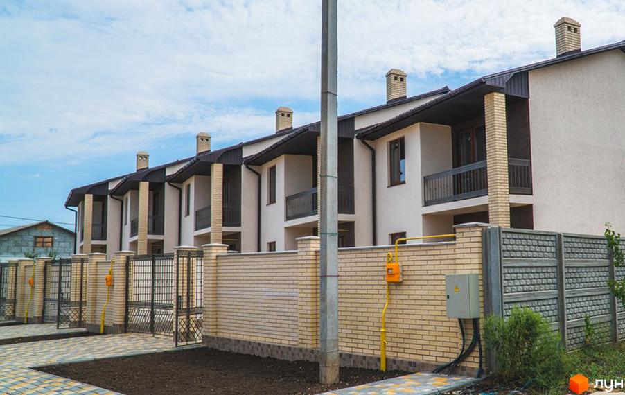 Житловий район «Червоний Хутір», вул. Таїровська, 41. Ряд будинків з бежевими фасадами, темними дахами та цегляним парканом.