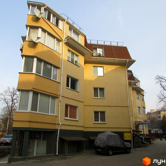 Зовнішній вигляд будинку по вулиці Українська, 85. Багатоповерхова будівля жовтого кольору з великими вікнами та коричневим дахом.