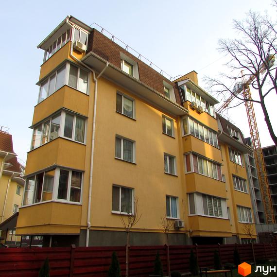 Зображення будинку на вулиці Українська, 85. Фасад жовтого кольору, коричневий дах, великі вікна та балкони. Навколо будинку зелені насадження та червоний паркан.