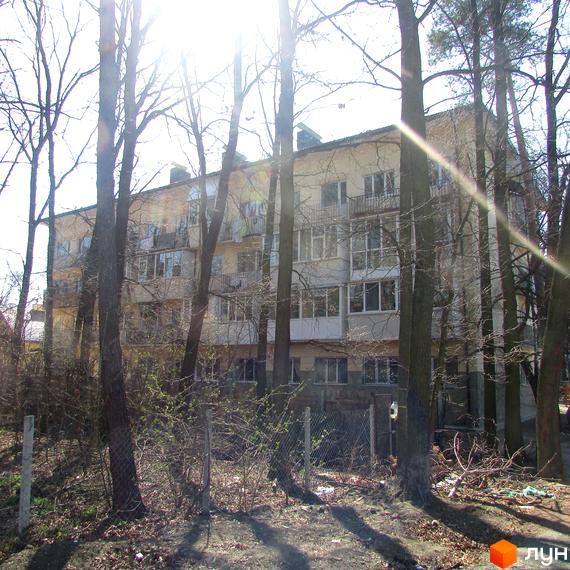 Зовнішній вигляд будинку по вул. Полтавська, 29. Багатоповерхова будівля з балконами, огороджена парканом, навколо дерева та кущі.