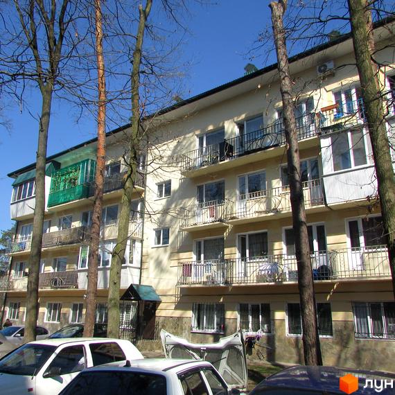 Зовнішній вигляд багатоквартирного будинку по вулиці Полтавській, 29. На передньому плані дерева та автомобілі.