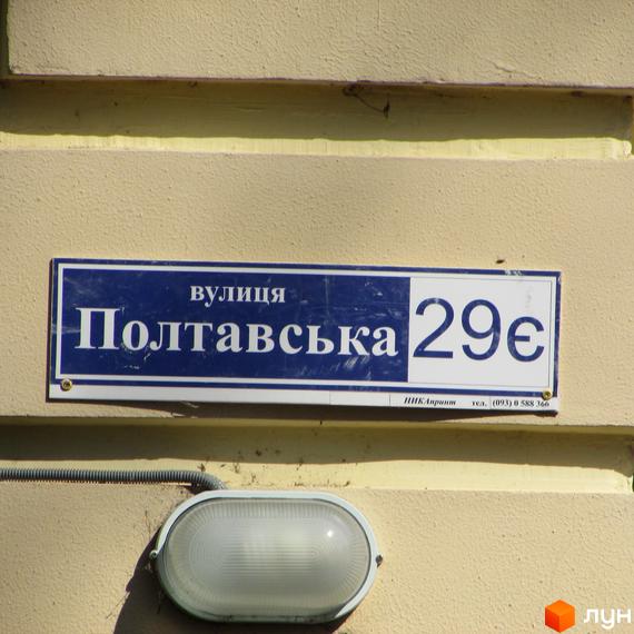 Фото будинку на вулиці Полтавська, 29. Табличка з назвою вулиці та номером будинку на фасаді світло-жовтого кольору.