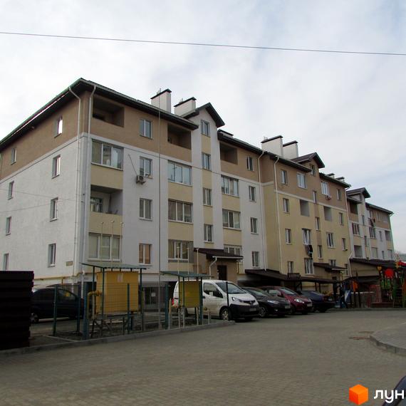 Фото фасаду та прибудинкової території Новобудови по вул. Новооскольська, 8в. Багатоповерховий будинок з парковкою та дитячим майданчиком.