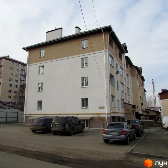 Фото фасаду будинку по вул. Новооскольська, 8в. Багатоповерхівка з парковкою для автомобілів біля будинку.