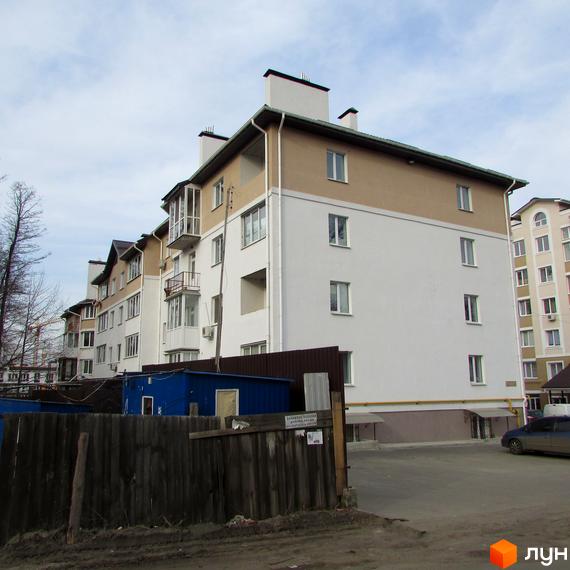 Зовнішній вигляд багатоквартирного будинку на вулиці Новооскольська, 8в. На фото прибудинкова територія з парковкою та огорожею.