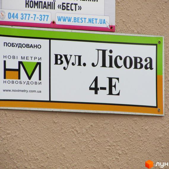 Інформаційна вивіска житлового комплексу Авангард на вул. Лісова 4-Е, що містить назву забудовника Нові Метри.