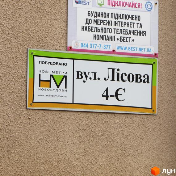 Знак з адресою: вул. Лісова, 4-Є. Побудовано Новобудовою Нові Метри. Інформація про підключення до інтернету та телебачення компанією 