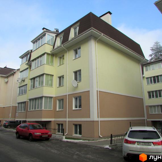 Зображення фасаду Житлового комплексу Авангард на „Лісовій“. Багатоповерховий будинок з мансардним дахом та припаркованими автомобілями.