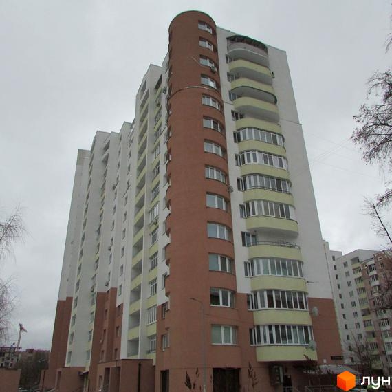 Житловий комплекс Княжа гора: багатоповерховий будинок з білими та коричневими фасадами, округлою частиною та заскленими балконами світло-жовтого кольору.