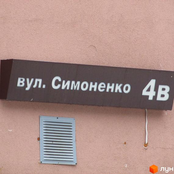 Вулична табличка з адресою вул. Симоненка 4В на фасаді Житлового комплексу Княжа гора. Видно частину стіни та вентиляційну решітку.