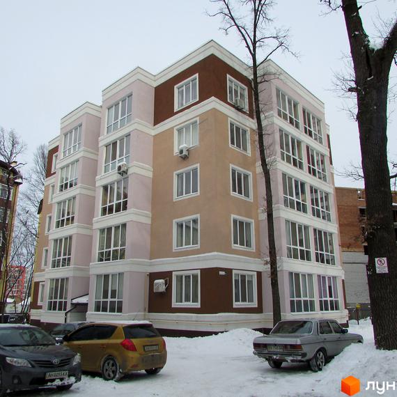 Житловий комплекс Фортуна з багатоповерховим фасадом у світлих та коричневих тонах. Прибудинкова територія вкрита снігом, припарковані автомобілі.