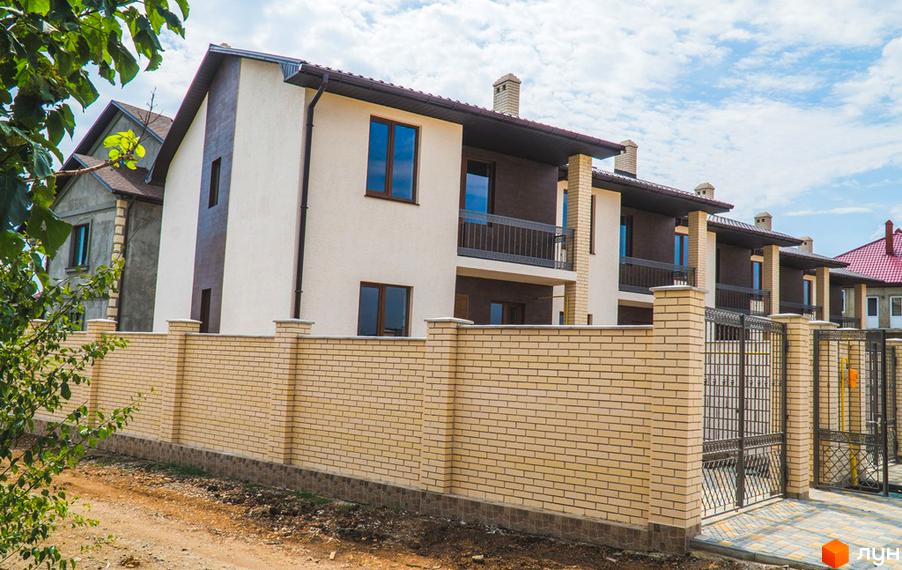 Ряд двоповерхових будинків ж/м «Червоний Хутір» на вул. Таїровська, 41, з бежевими та коричневими фасадами. Перед будинками світлий цегляний паркан та металеві ворота.