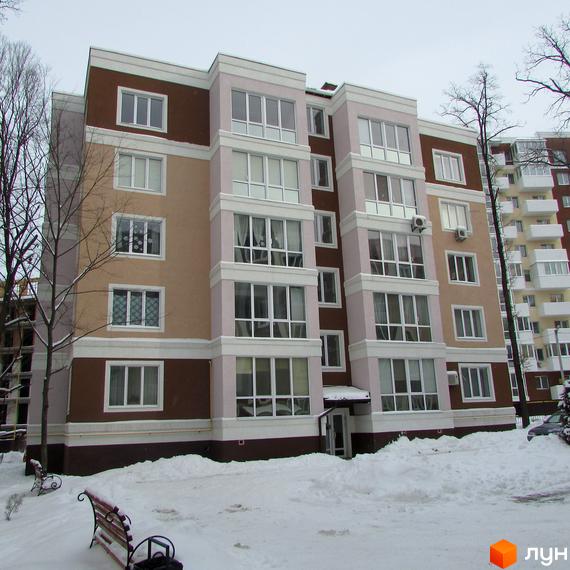 Новобудова Фортуна з коричневими, бежевими та світло-рожевими фасадами, білими вікнами та балконами. Прибудинкова територія вкрита снігом з деревами та лавками.